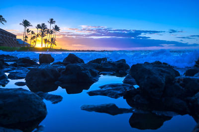 Rocks on sea shore against sky during sunset