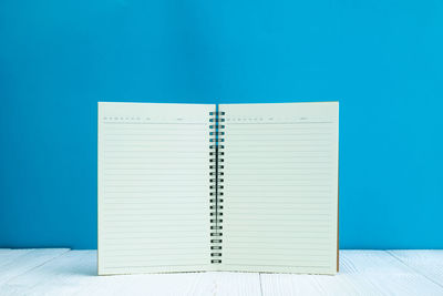 Close-up of open book on table against blue background