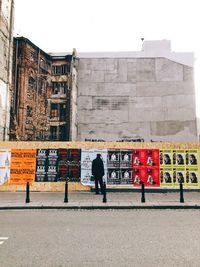 Rear view of man walking on street against building