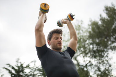 Low angle view of man holding bottle against blurred background