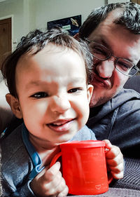 Portrait of smiling boy drinking water at home