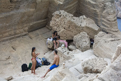 High angle view of people sitting on rock