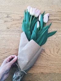 Cropped image of person hand touching tulips on table