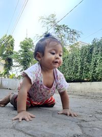 Low angle view of cute baby girl crawling on land against sky