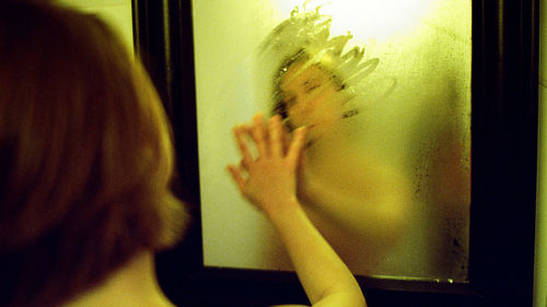 The beautiful woman with wet hair looks in a mirror in a bathroom