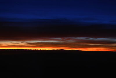 Silhouette landscape against dramatic sky during sunset