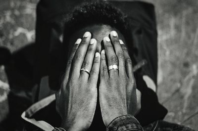 Close-up of man covering face with hands