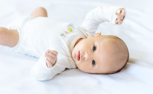 Portrait of cute baby girl lying on bed at home