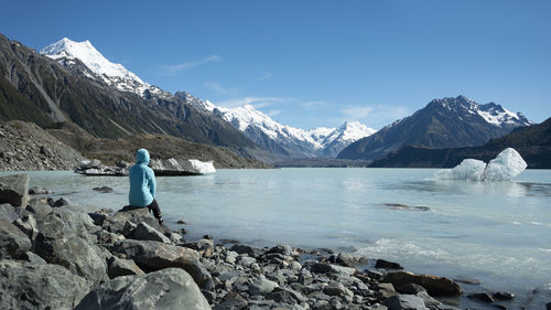 Rear view of person looking at snowcapped mountains against sky