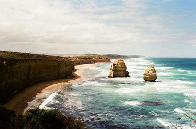 Rock formations in great ocean road against cloudy sky