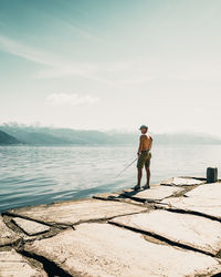 Rear view of man standing in sea against sky