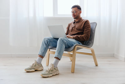 Young woman using laptop while sitting on sofa at home