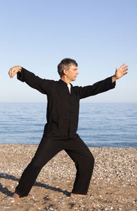 Full length of man doing martial arts at beach