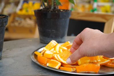 Cropped image of hand picking oranges in plate