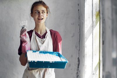 Portrait of young woman standing against wall