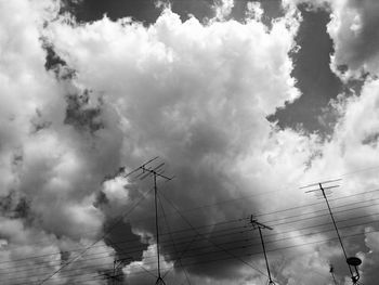 Low angle view of electricity pylon against cloudy sky