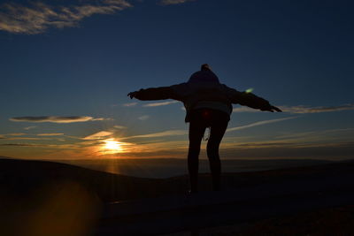 Rear view of silhouette man standing against sky during sunset