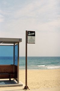 Information sign on beach against sky