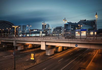 Train on bridge in city against sky at dusk