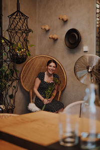 Portrait of young woman standing by glass on table
