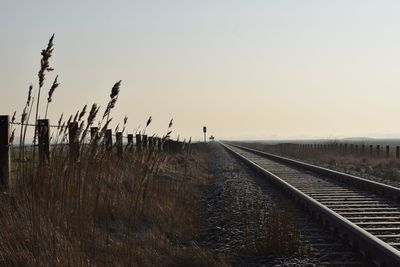 Railroad tracks against clear sky during sunset