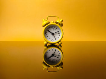 Close-up of clock against yellow background