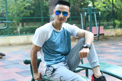 Portrait of young man sitting on sunglasses