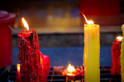 Close-up of burning candles against illuminated building