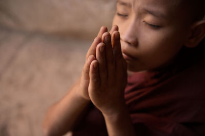 High angle view of boy with hands clasped praying