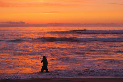 Silhouette of amateur fisherman in the sunset, sport fishing, recreational fishing on the beach