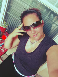 Portrait of young woman wearing sunglasses at home