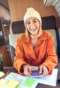 Portrait of smiling woman wearing knit hat using phone in van