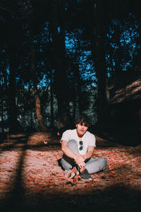 Young man sitting on land in forest