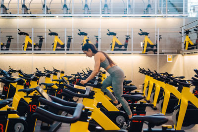 Side view of young female athlete on cardio bike in modern gym