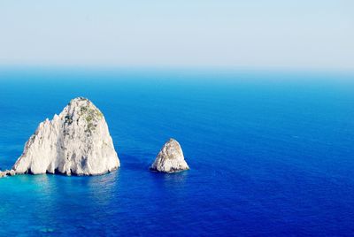 Rock formation in sea against clear sky
