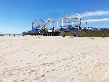 Ferris wheel on beach against blue sky