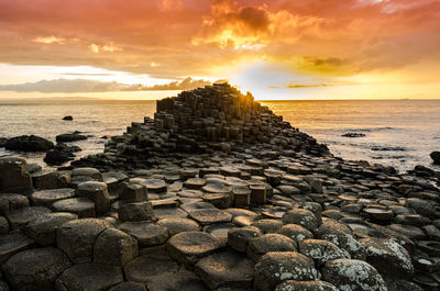 Stacked rocks at beach against sky during sunset