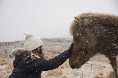 Close-up of woman touching horse during winter