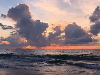 Scenic view of sea against cloudy sky at sunset