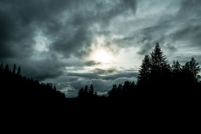 Silhouette of trees against cloudy sky