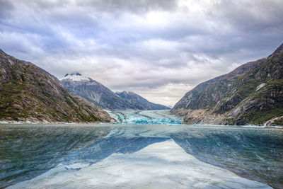 Scenic view of lake by mountains against sky