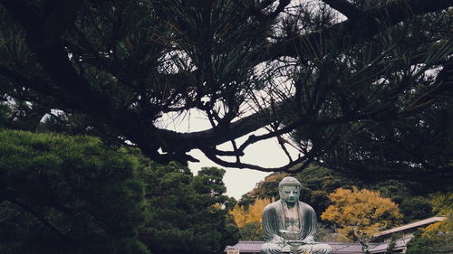 Statue amidst trees against sky