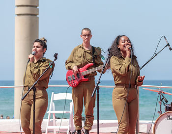 Friends standing by sea against clear sky