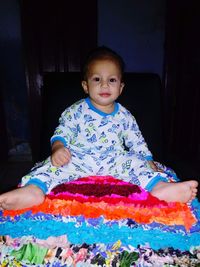 Portrait of cute boy sitting on sofa at home