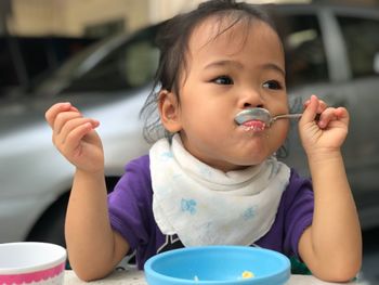 Close-up of girl having food at table in yard