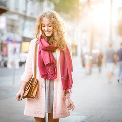 Smiling woman with scarf and purse on street looking down