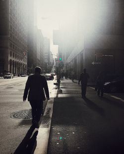 Rear view of silhouette man walking on street in city