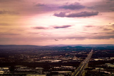 Aerial view of cityscape against cloudy sky at sunset