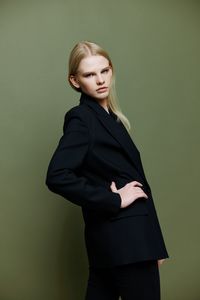 Young woman standing against yellow background