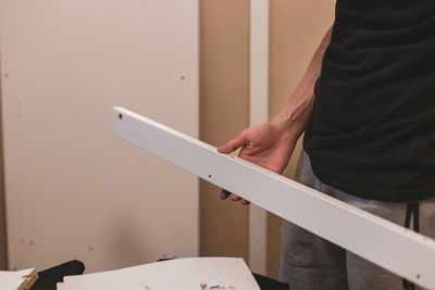 A young man holds a board from the closet in his hands.